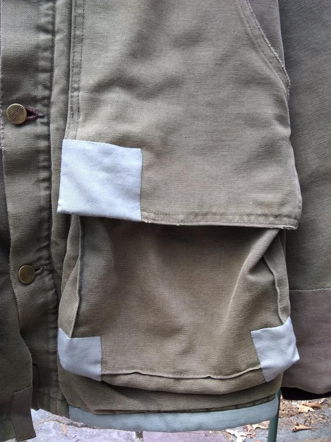 patches on the pocket and hem of a Carhartt jacket