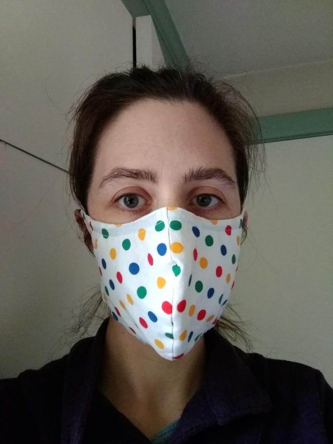 front view of woman wearing white/multi polka dot fitted face mask
