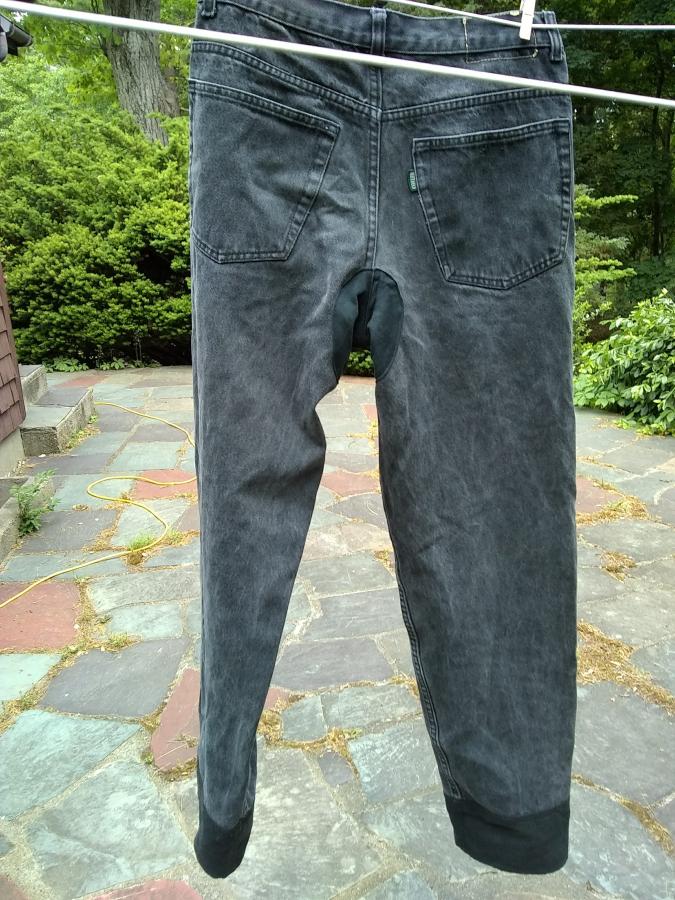 back view on clothesline of black jeans with leg extensions and crotch patch