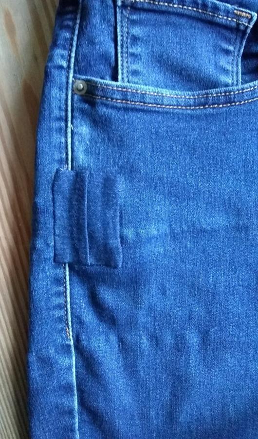 Closeup of jeans with patch over hole on side of pocket