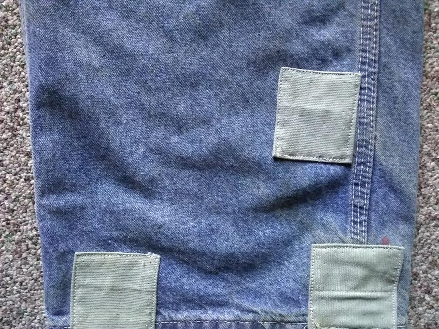 closeup of bottom of leg of blue jeans with three small green patches