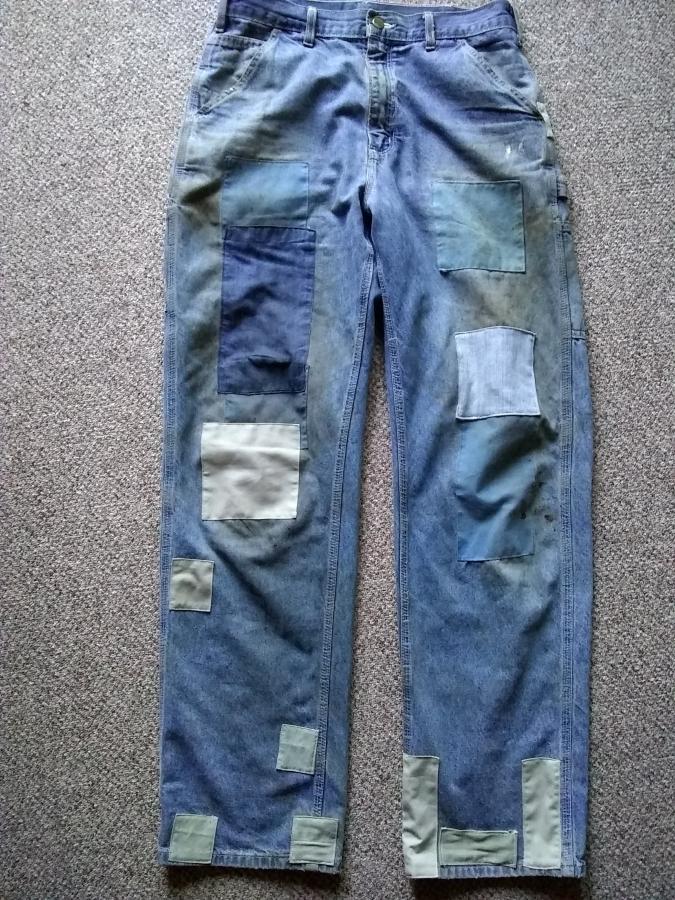 front, full view of blue jeans with many, many patches in blue and pale green