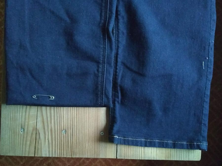 closeup of bottom of blue jean legs with one leg folded up to indicate new desired length