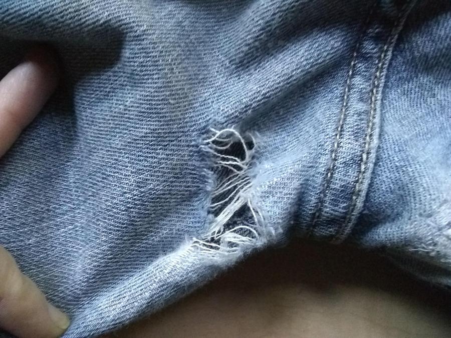 closeup of hole in blue jeans, just left side of backside