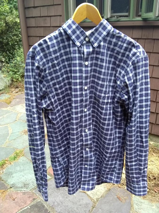 Plaid shirt with not very visible rip in elbow, on coat hanger outside