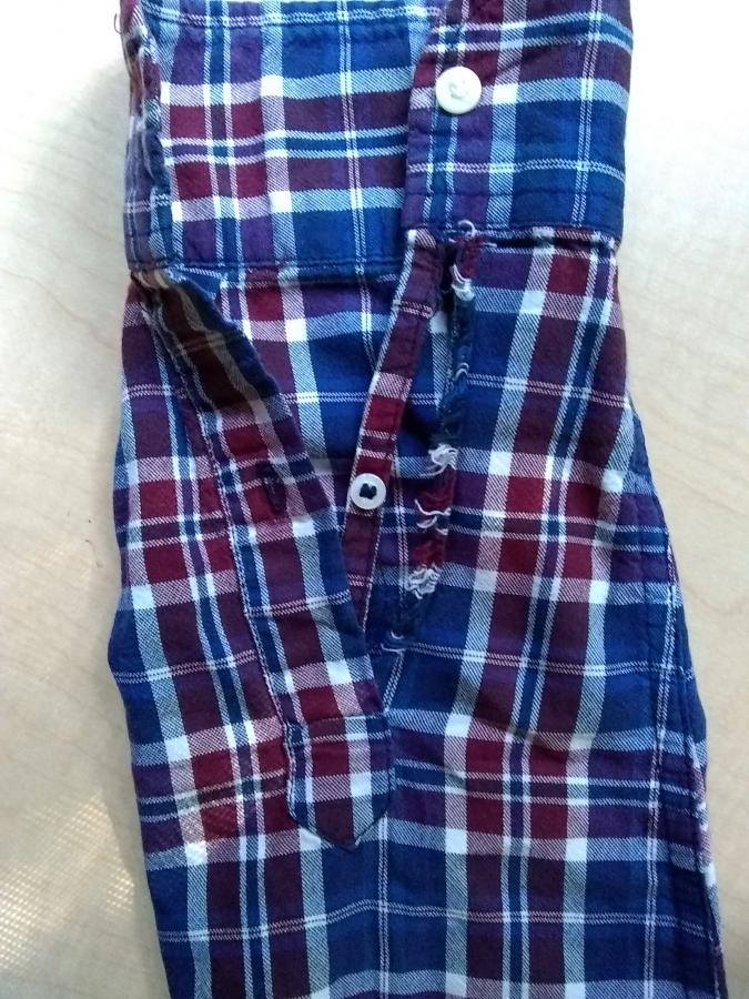 sleeve of plaid shirt with long rip by wrist and forearm