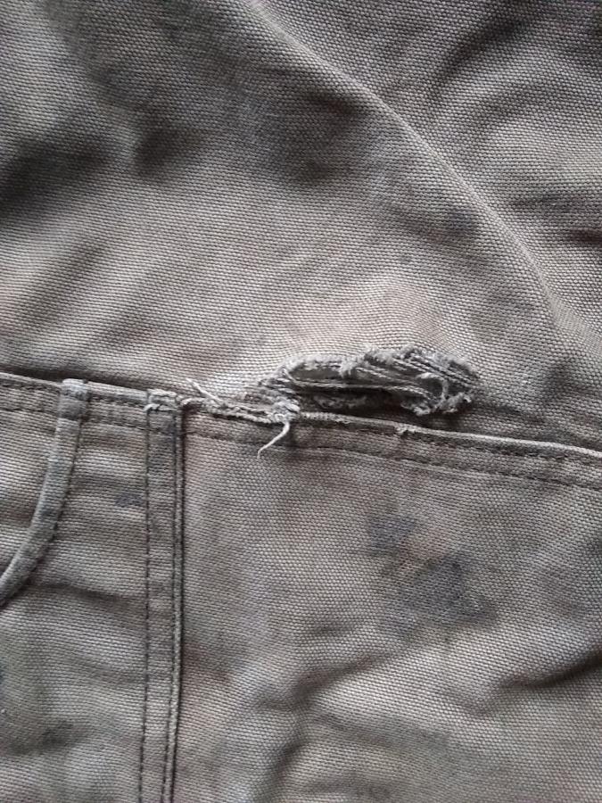 closeup of rip on brown/gray work pants