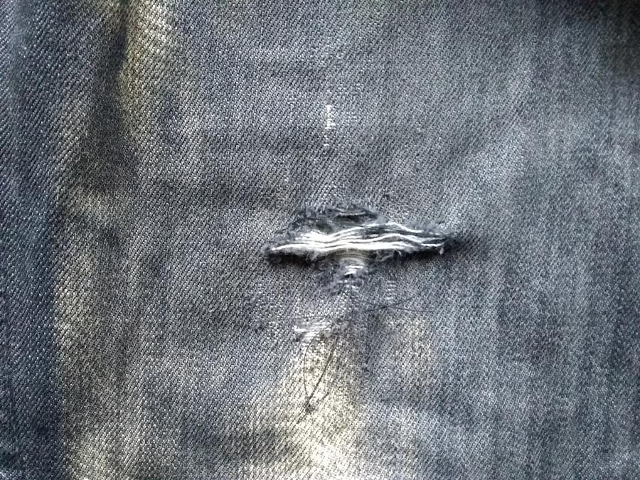 closeup of large hole in jeans