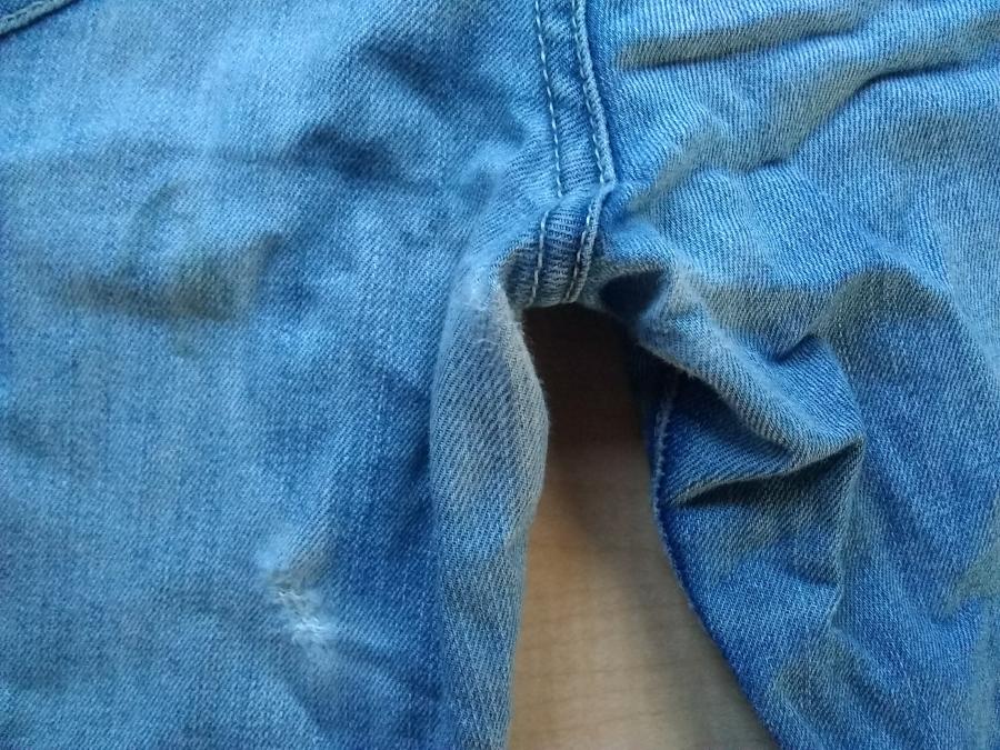 closeup of blue jeans showing worn fabric at inner thigh and crotch