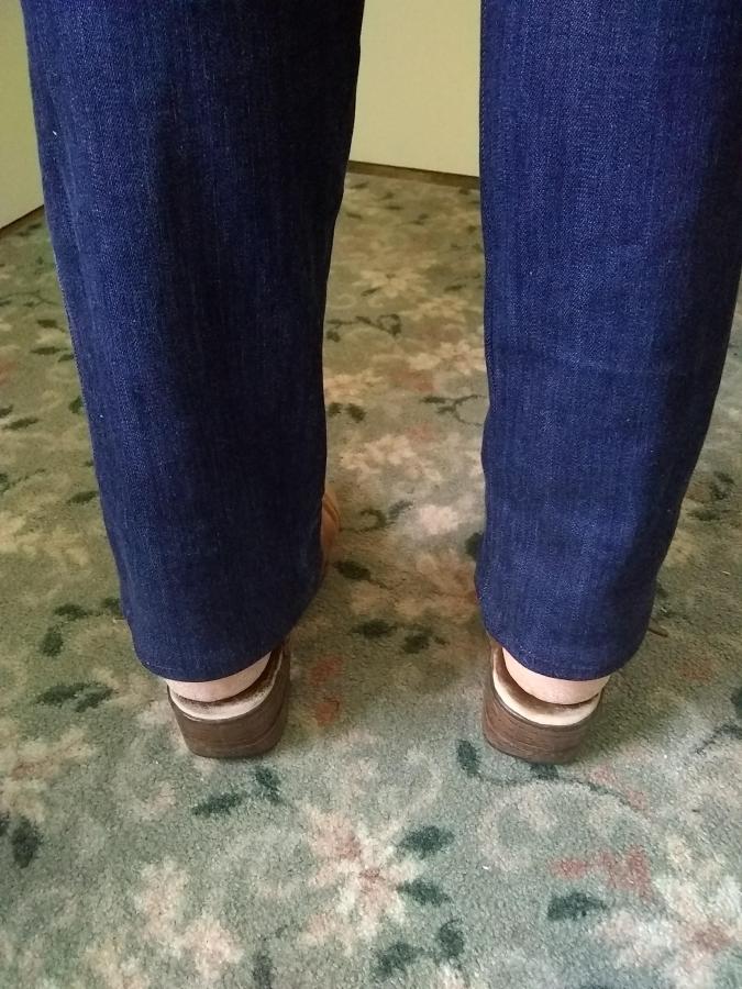 back view of woman's feet and ankles in appropriate length dark blue jeans