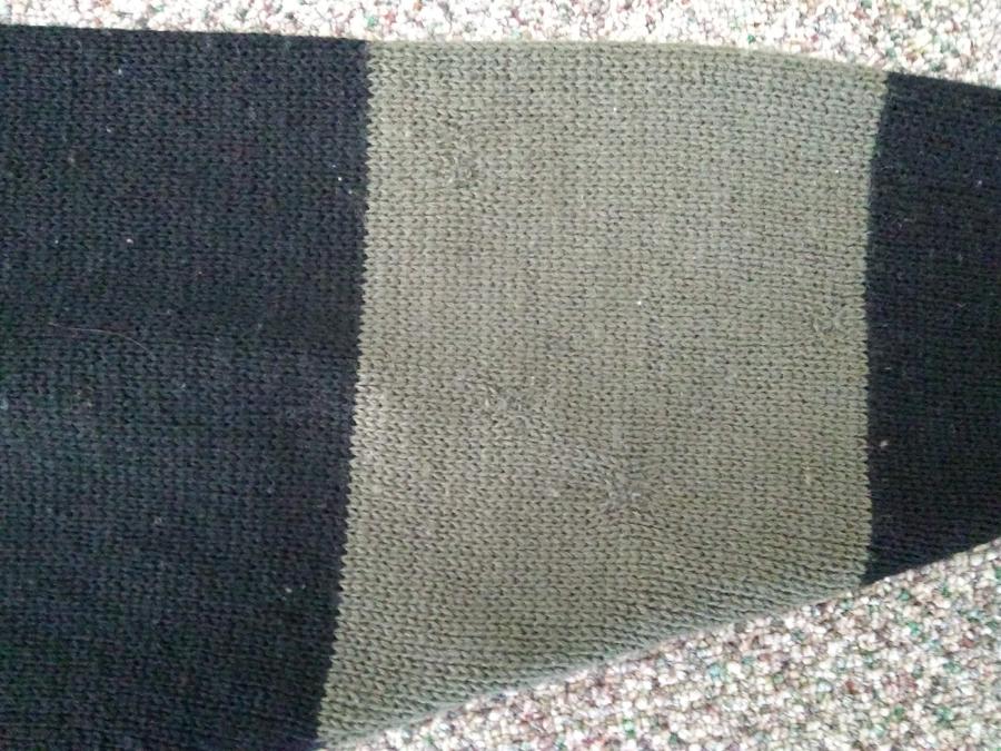 closeup of mended sleeve, back of olive and black sweater