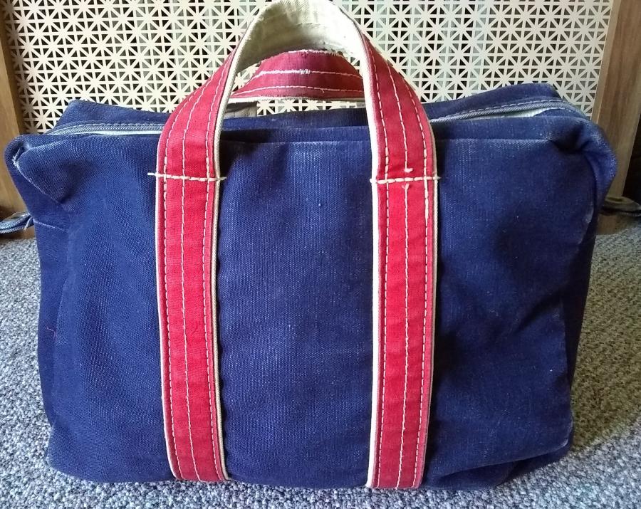 blue tote bag with red handles standing upright