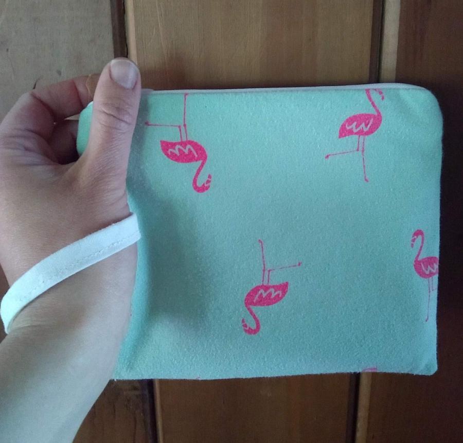 wristlet (little purse with wrist strap), pale green with pink flamingos, held in hand with white wrist loop
