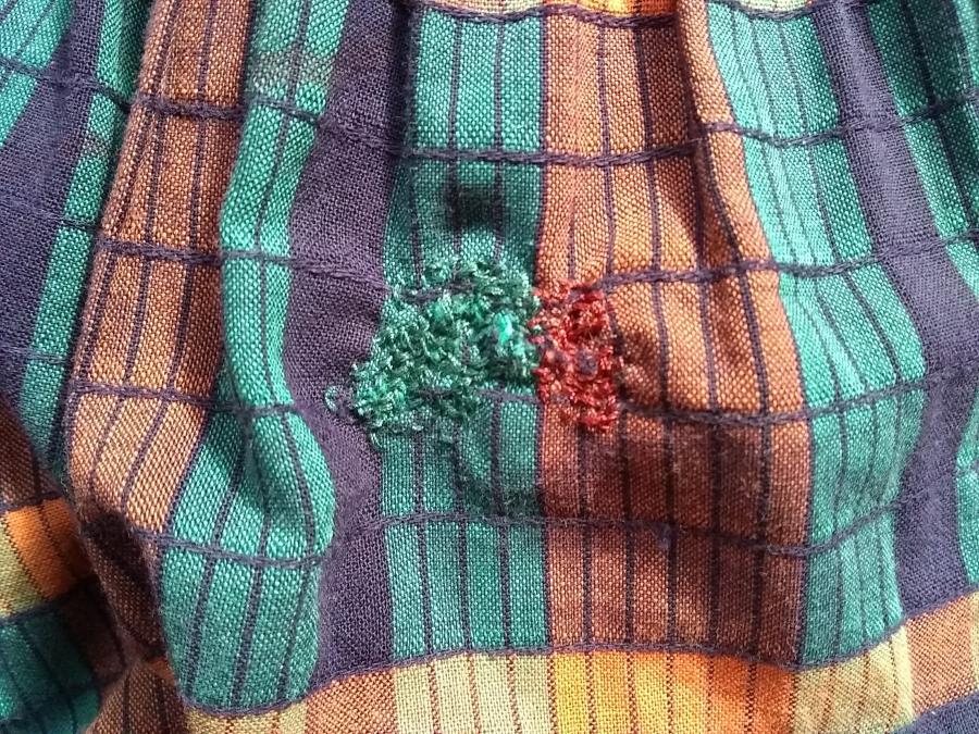 green/orange/navy/yellow plaid-ish fabric with a green and orange darn in the center