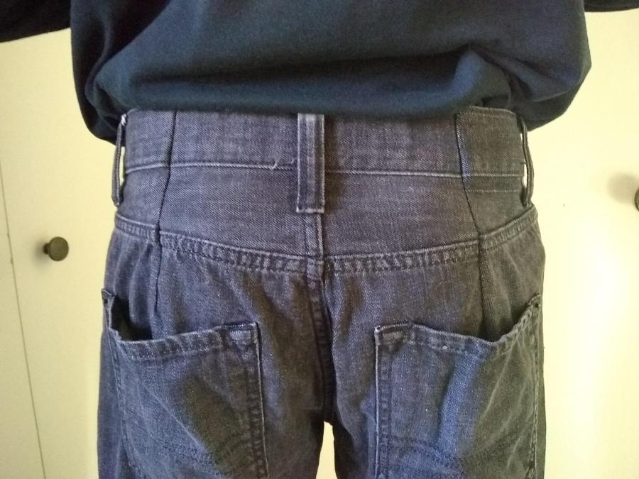 back view of man wearing jeans, shown from waist to back pockets; two darts are visible at waist