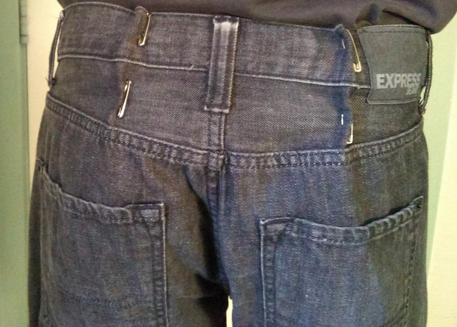 back view of man wearing jeans, shown from waist to back pockets, with safety pins cinching in the over-large waist