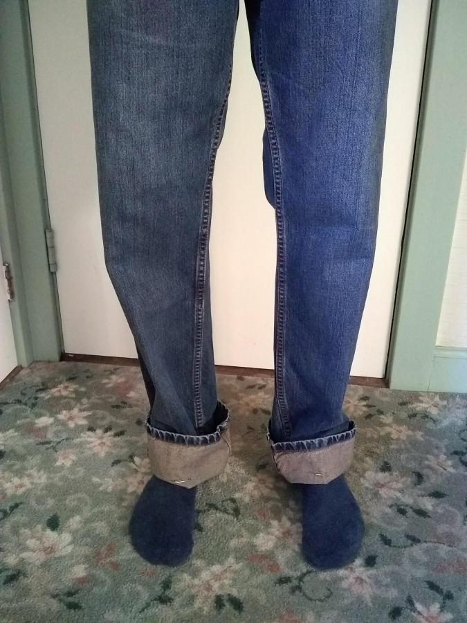 front view of man's legs in blue jeans that are too long (cuffs folded up 3 inches or so)