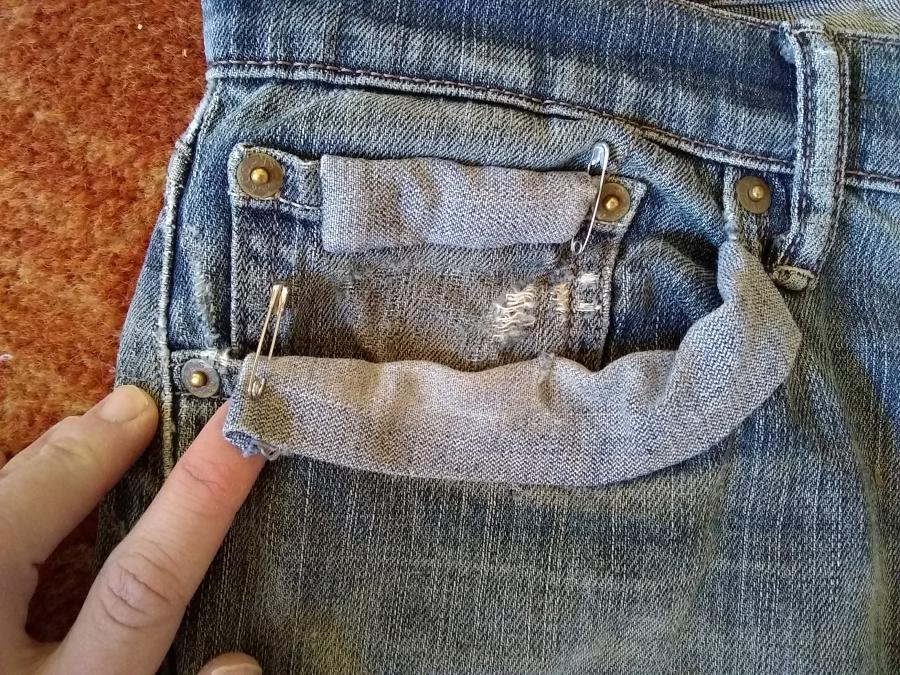 closeup of pocket including coin pocket in jeans. Coin pocket is frayed and patch over pocket opening is coming off