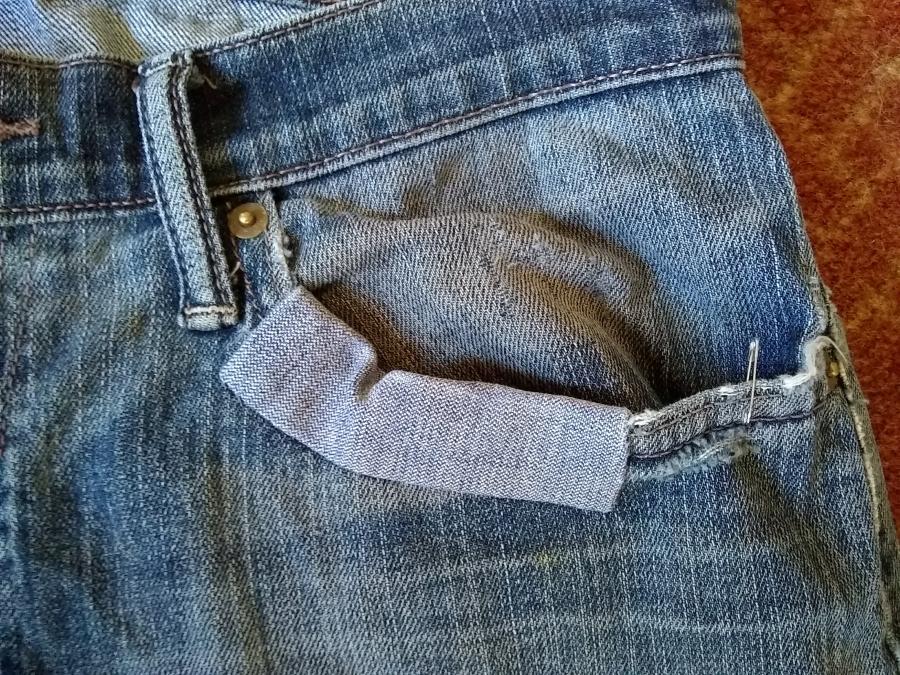 Front pocket of jeans, showing fraying fabric at pocket opening