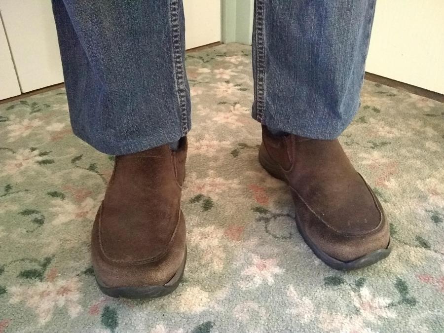 closeup of man's feet and ankles in blue jeans that end just above his shoes