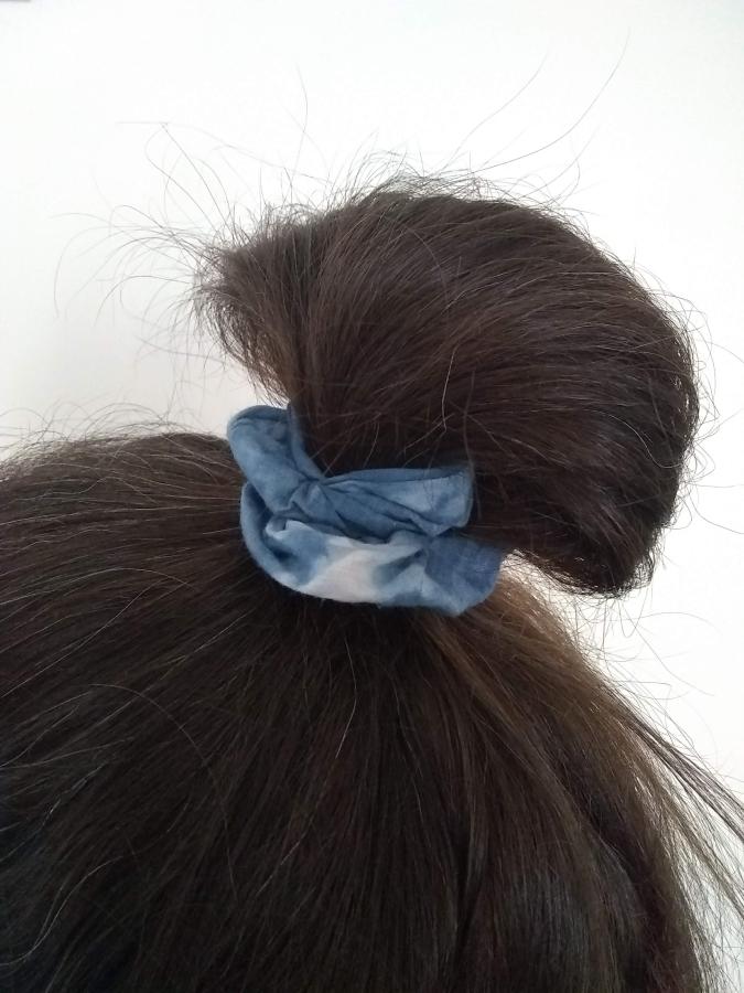 Mostly brown hair in messy bun secured by blue tie-dye scrunchie, view from top