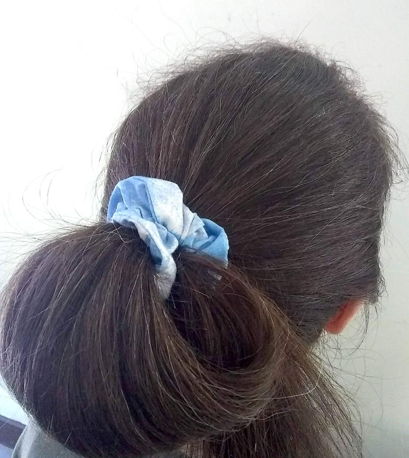 back of woman's hair (brown with a bit of gray) wearing pale blue/white scrunchie