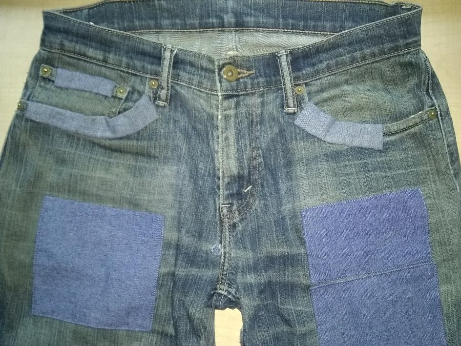 top front of blue jeans with patches
