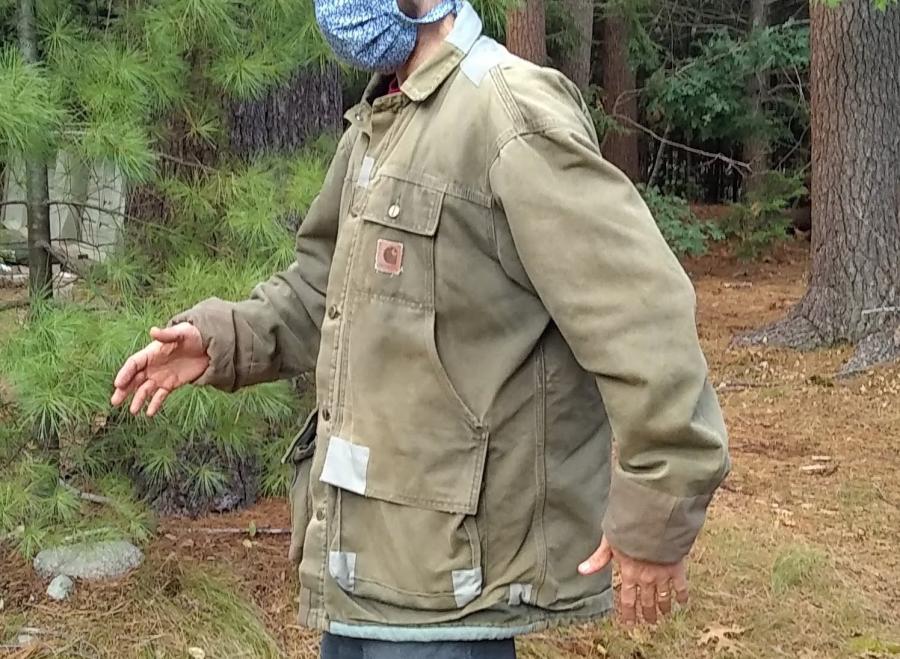 sideview of patched Carhartt jacket on man in the woods