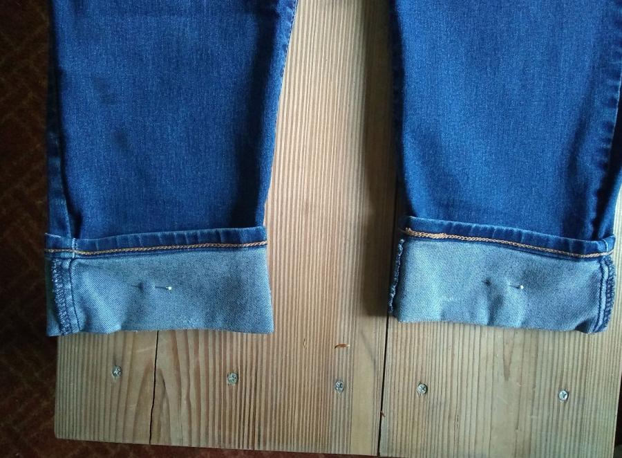 Closeup of cuffs of blue jeans on wooden background