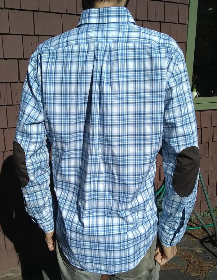 back view of blue plaid shirt with elbow patches, worn by man