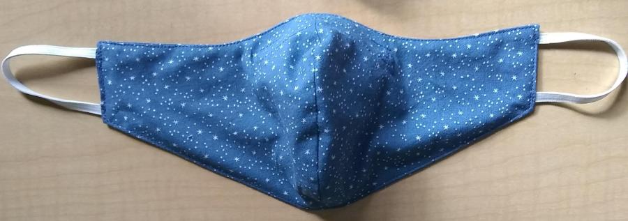 fitted face mask in blue star print with elastic earlobes on wooden backround