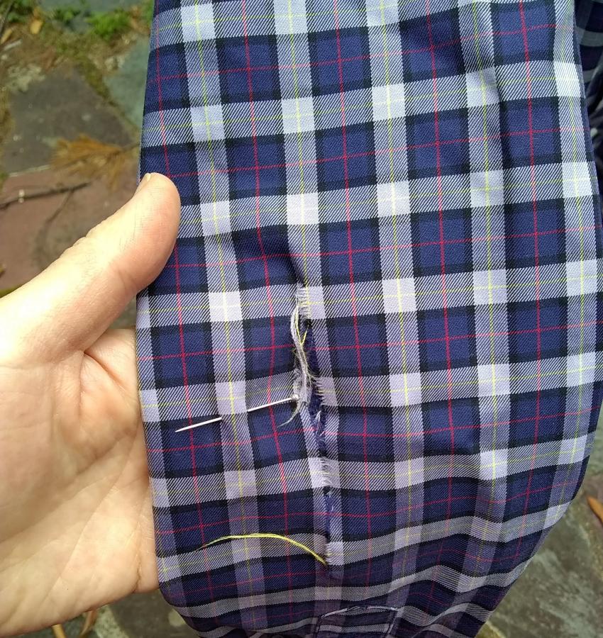closeup of rip in sleeve of plaid shirt