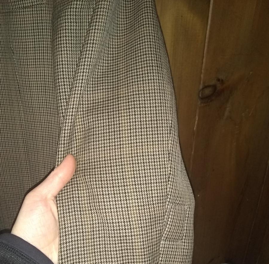 hand holding sleeve of sport coat with small matching patch