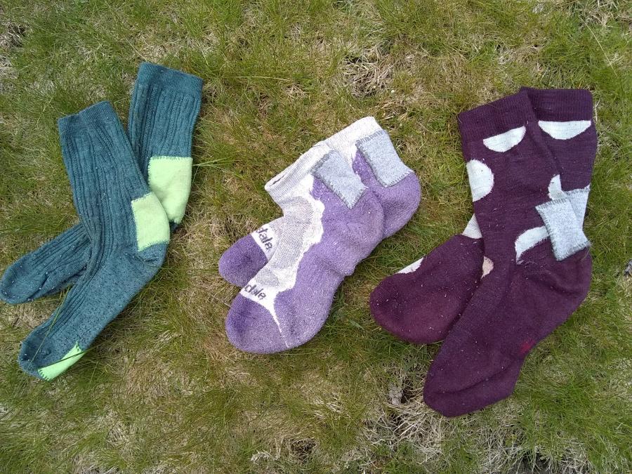 Three pairs of socks, all patched, on grass