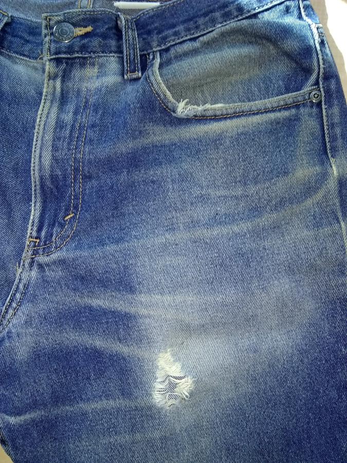 right side of jeans with hole in upper thigh and worn pocket