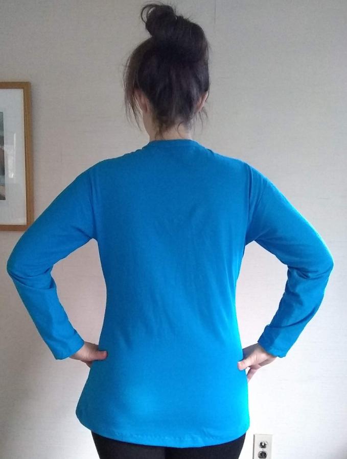 back view of woman wearing long sleeve turquoise henley shirt, tunic length with slightly shaped side seams