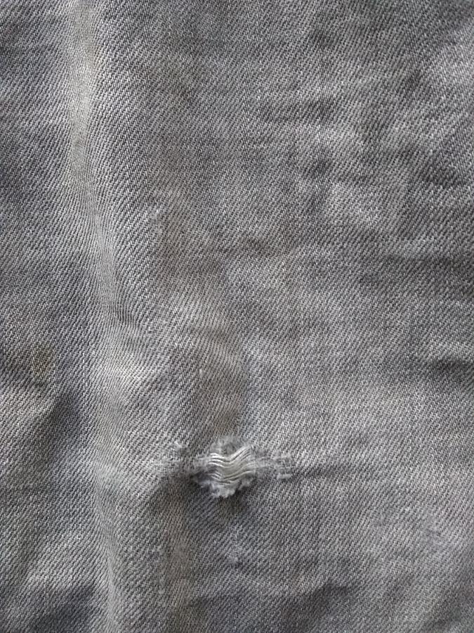 closeup of hole in gray jeans