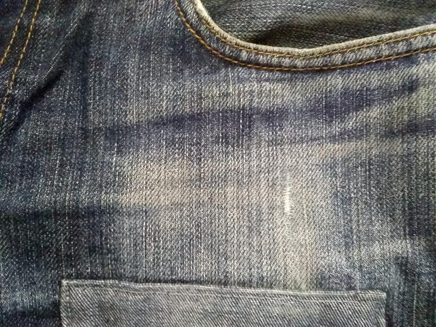 closeup of jeans front with exiting patch and small new  hole over pocket