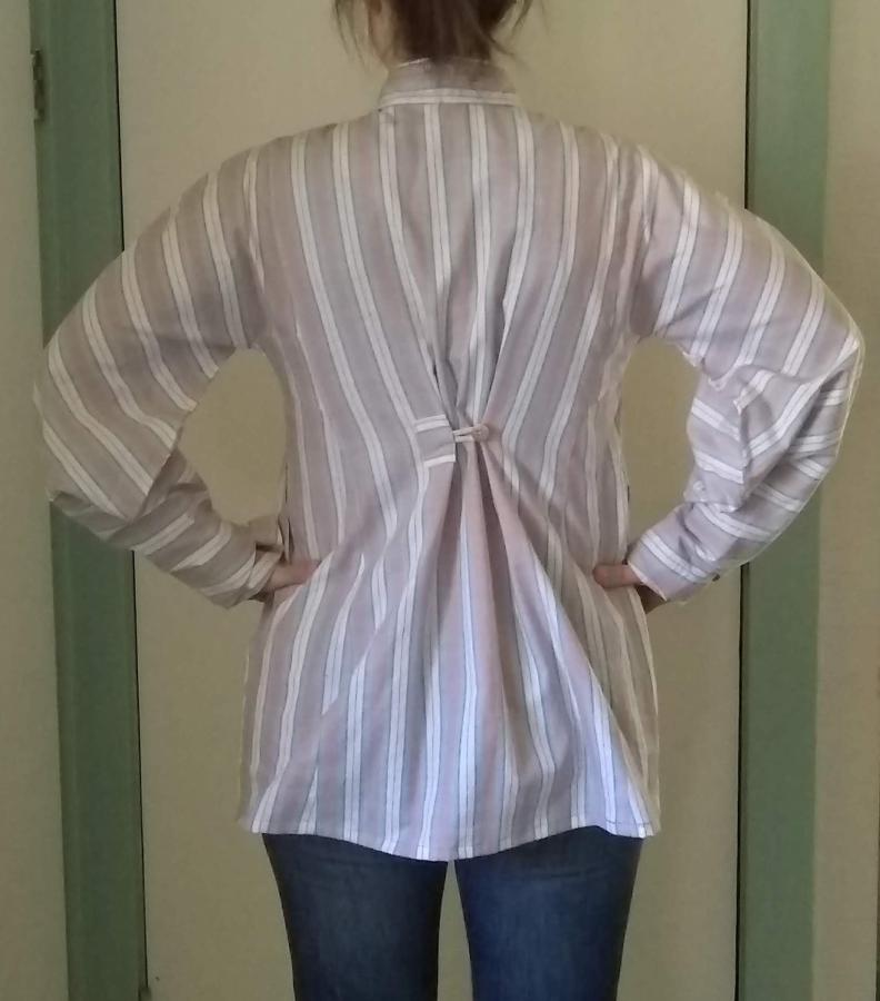 back view of woman wearing striped woven shirt with tapered sleeves and cinching via button at upper back