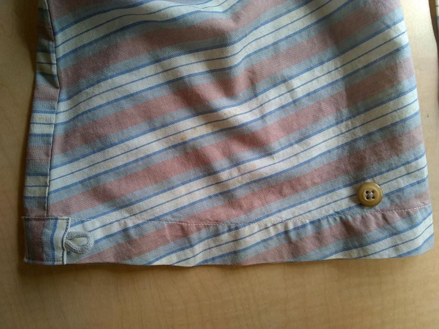 closeup of button and button loop at sleeve of striped woven shirt