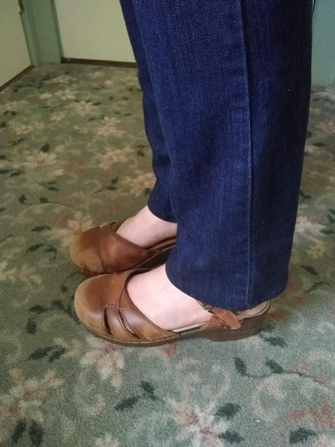 side view of woman's feet and ankles in correctly hemmed dark blue jeans and brown leather shoes