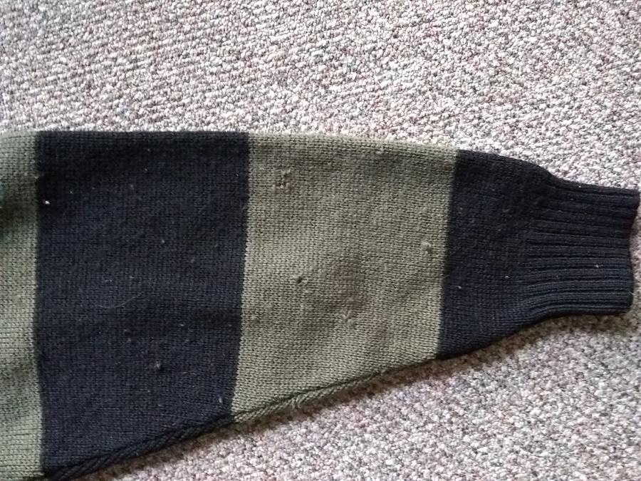 back view of holes on the sleeve of olive and black sweater