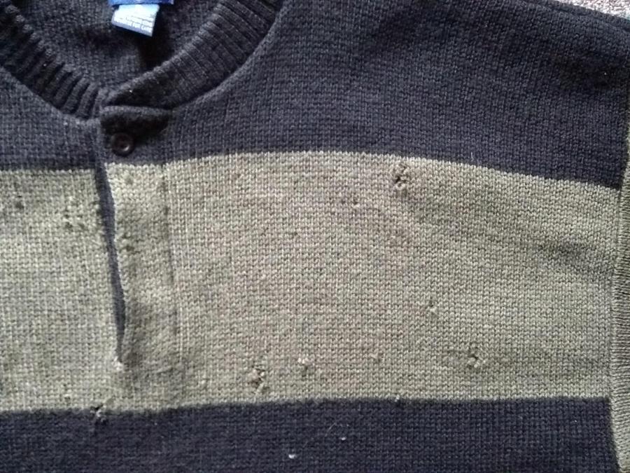 closeup of holes in front top left side of olive and black sweater