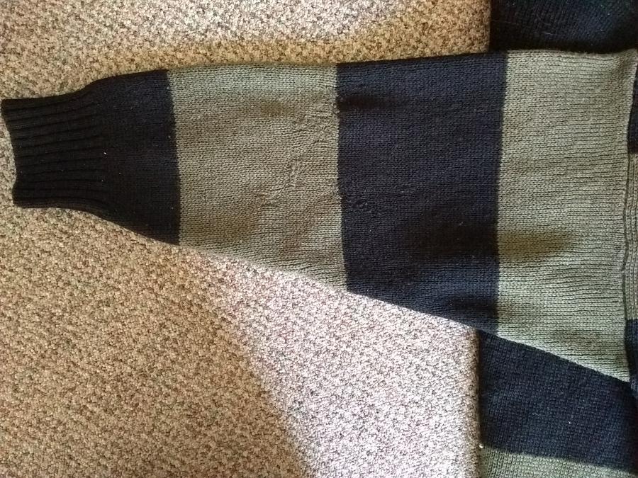 mended sleeve, front view, of olive and black sweater