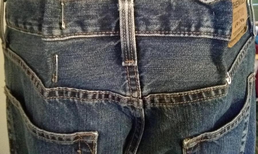 man in blue jeans, just back waist/hip; jeans are pinned with safety pins at waist because they are too big