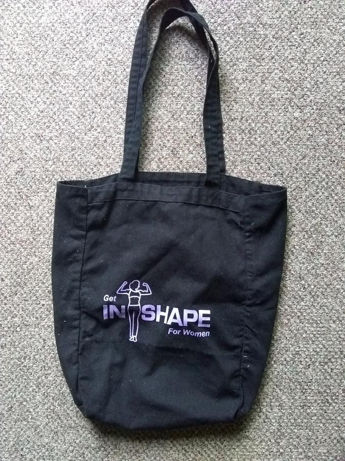 black tote bag with "in shape for women" logo screen printed on it in purple
