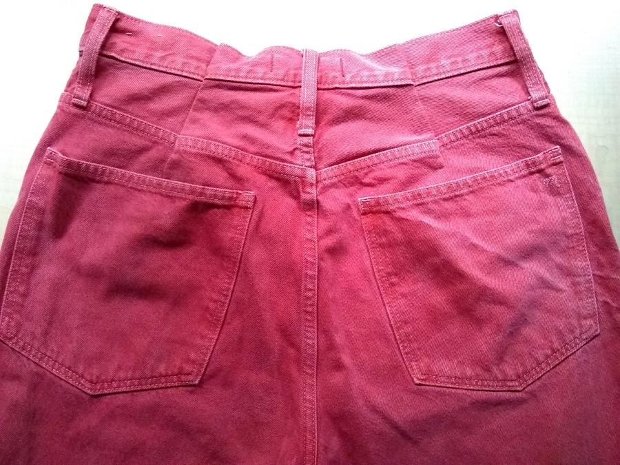 closeup of the seat of red jeans, with two darts of sewing visible one either side of center belt loop