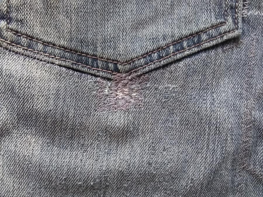 closeup of back pocket of jeans, with machine darning visible just below the point of the pocket