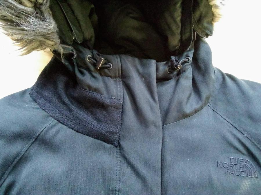 Black North Face winter coat with fur on hood and black patch sewn onto collar