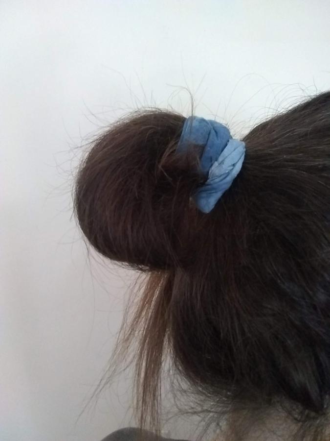 Mostly brown hair in messy bun secured by blue tie-dye scrunchie